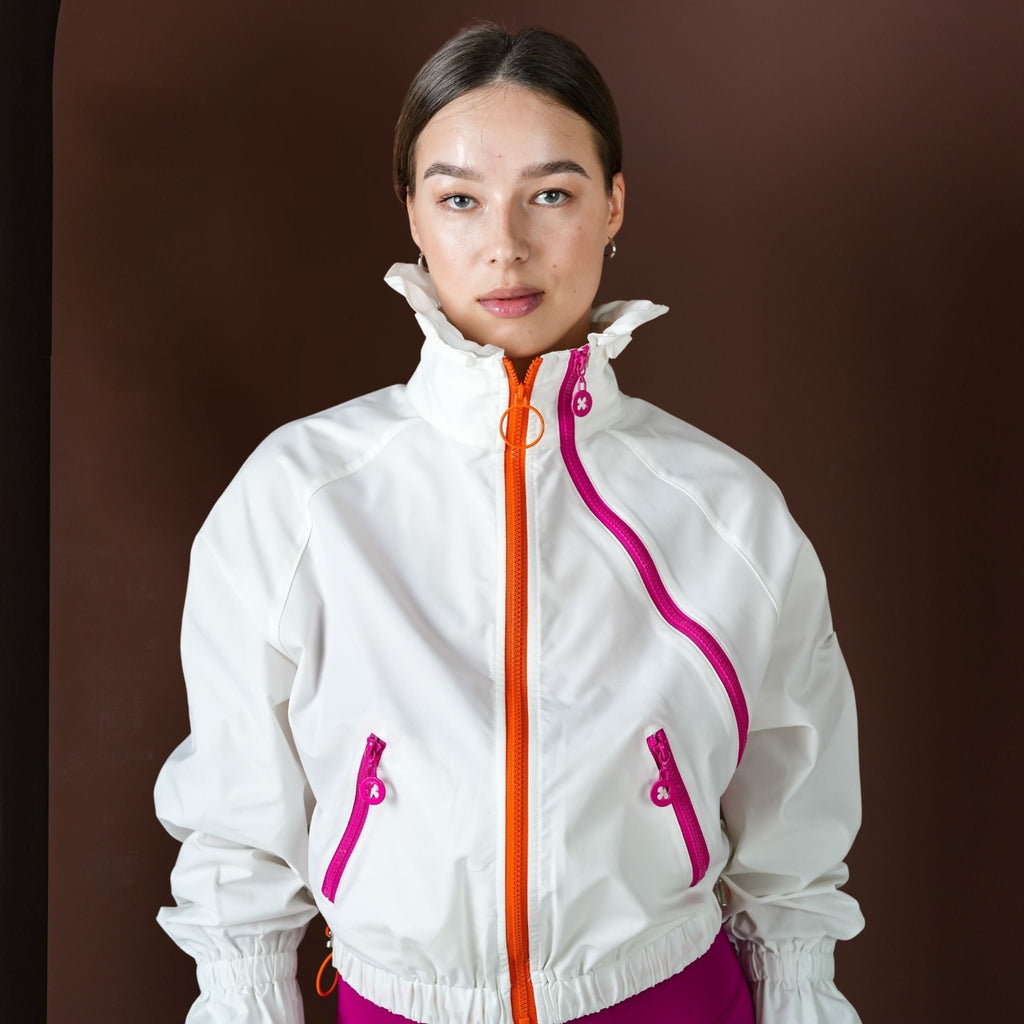 Person wearing a white jacket with pink accents on a brown background