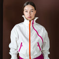 Person wearing a white jacket with pink accents on a brown background