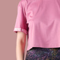 Pink t-shirt with rolled-up sleeves and colorful pants on a beige background